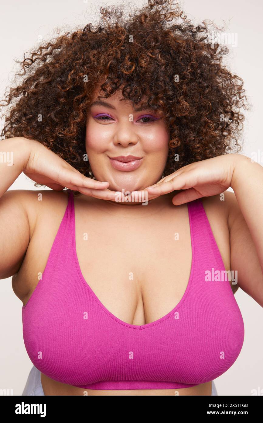 Femme brune avec les cheveux bouclés, portant un soutien-gorge rose Banque D'Images
