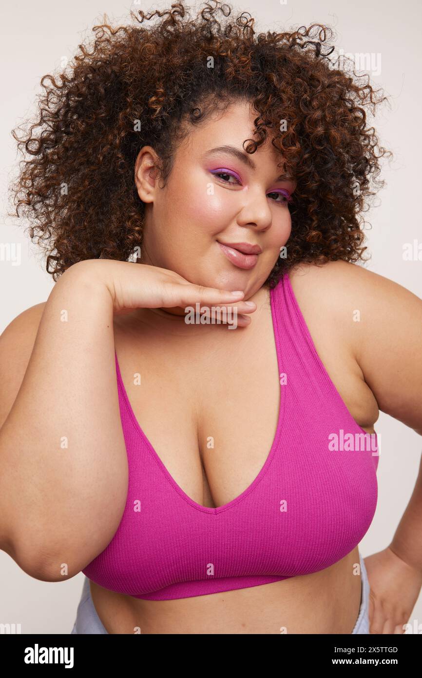 Femme brune avec les cheveux bouclés, portant un soutien-gorge rose Banque D'Images