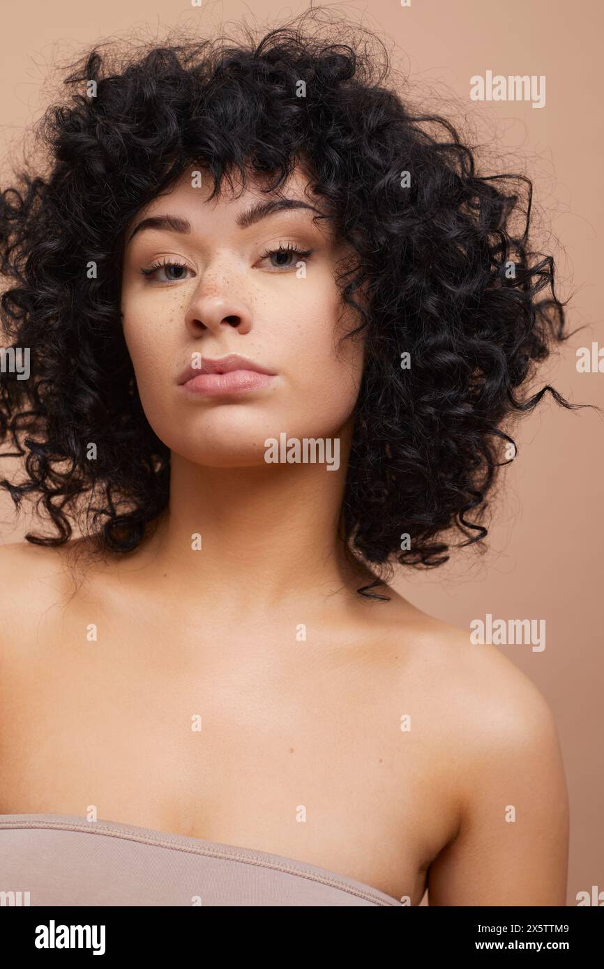 Portrait studio de belle femme sérieuse avec des cheveux bouclés et des taches de rousseur Banque D'Images