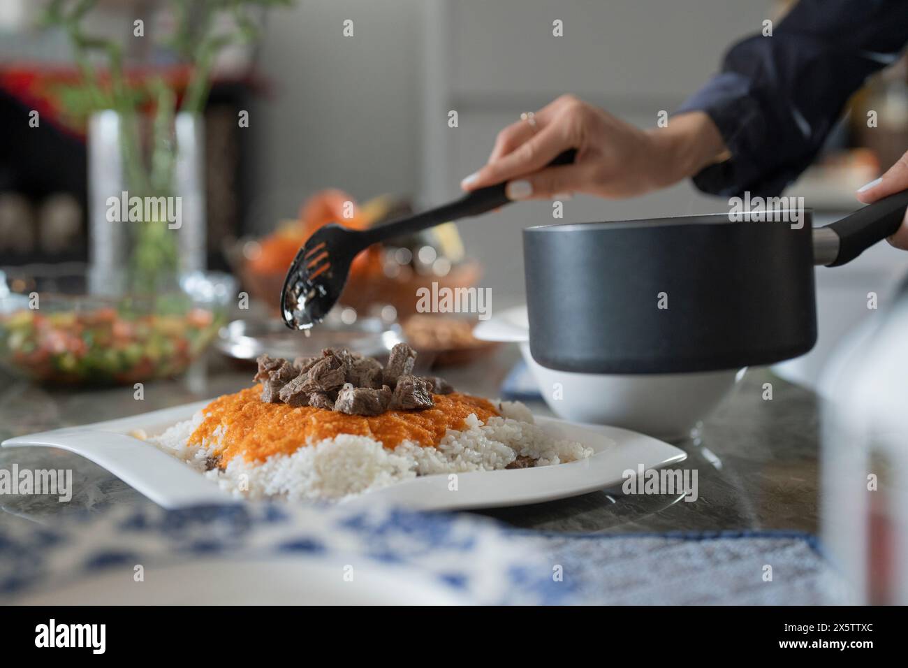 Femme mettant de la nourriture maison dans l'assiette Banque D'Images