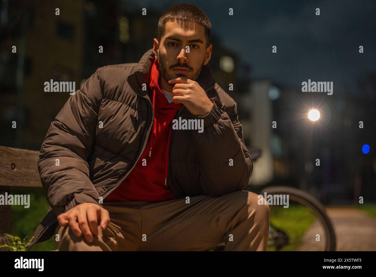 Portrait d'un jeune homme assis sur un banc la nuit Banque D'Images