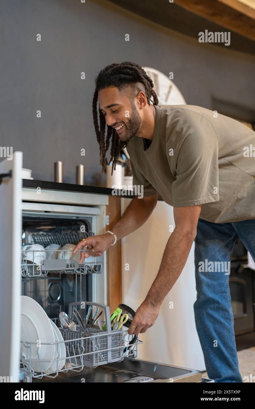 Homme avec des dreads chargement lave-vaisselle Banque D'Images