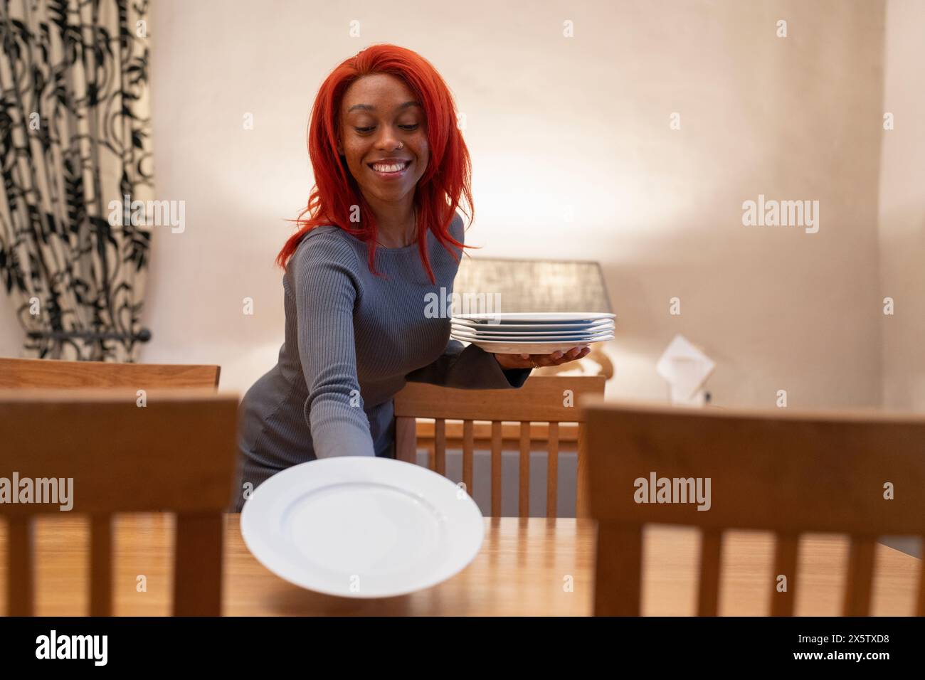 Femme rousse souriante dressant la table pour le dîner Banque D'Images