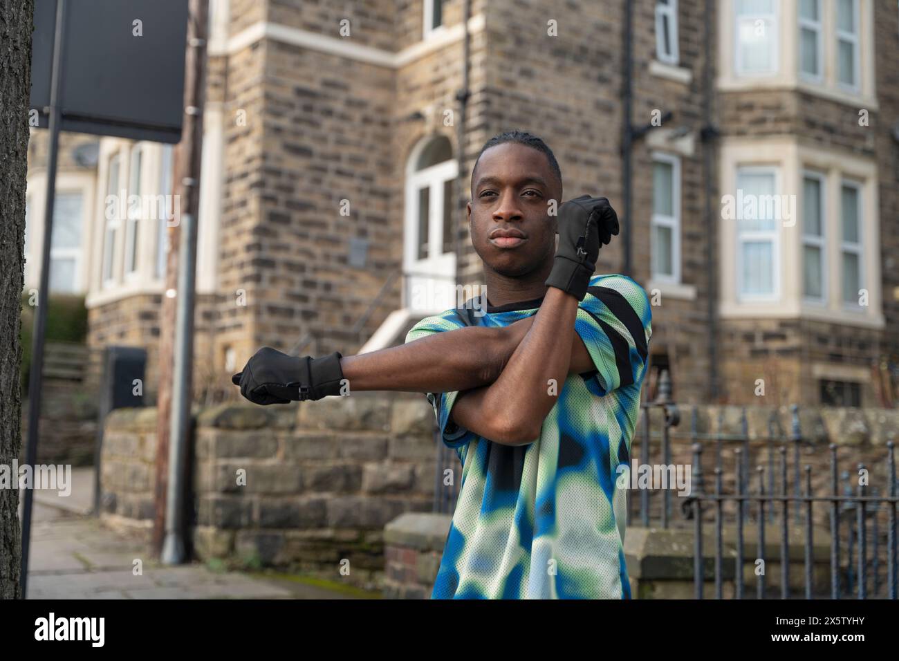 Portrait d'athlète étirant la jambe devant la maison de ville Banque D'Images