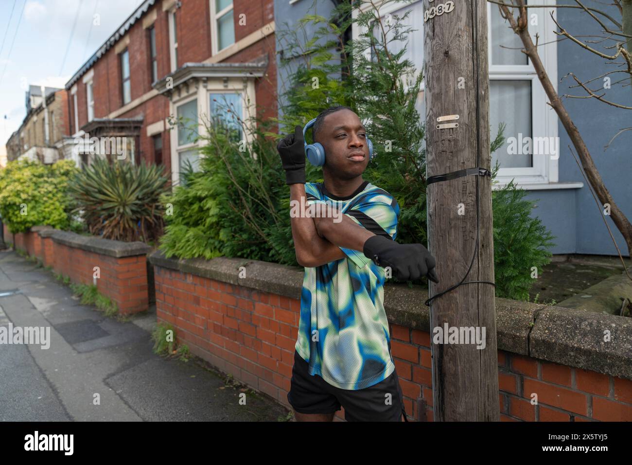 Portrait d'athlète étirant la jambe devant la maison de ville Banque D'Images