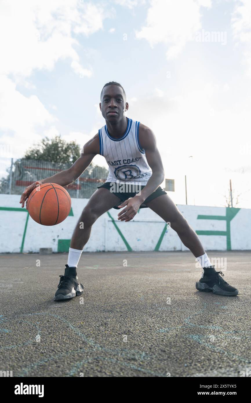 Homme rebondissant ballon de basket-ball sur un terrain de sport Banque D'Images