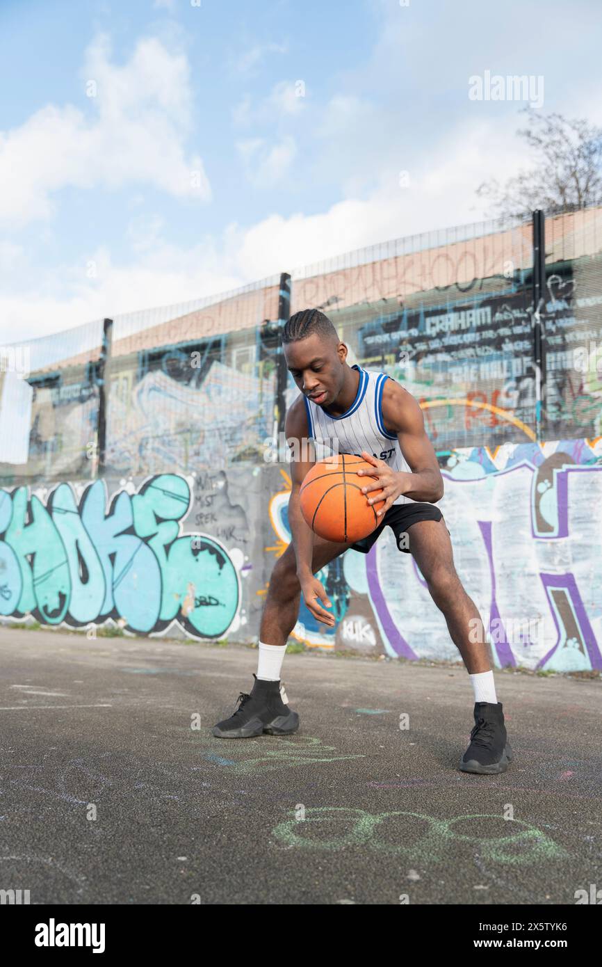 Homme rebondissant ballon de basket-ball sur un terrain de sport Banque D'Images