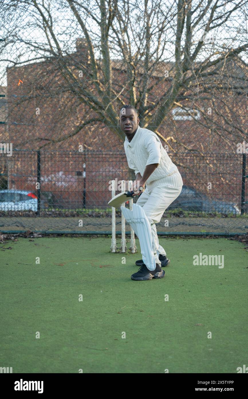 Homme jouant au cricket sur un terrain de sport extérieur Banque D'Images