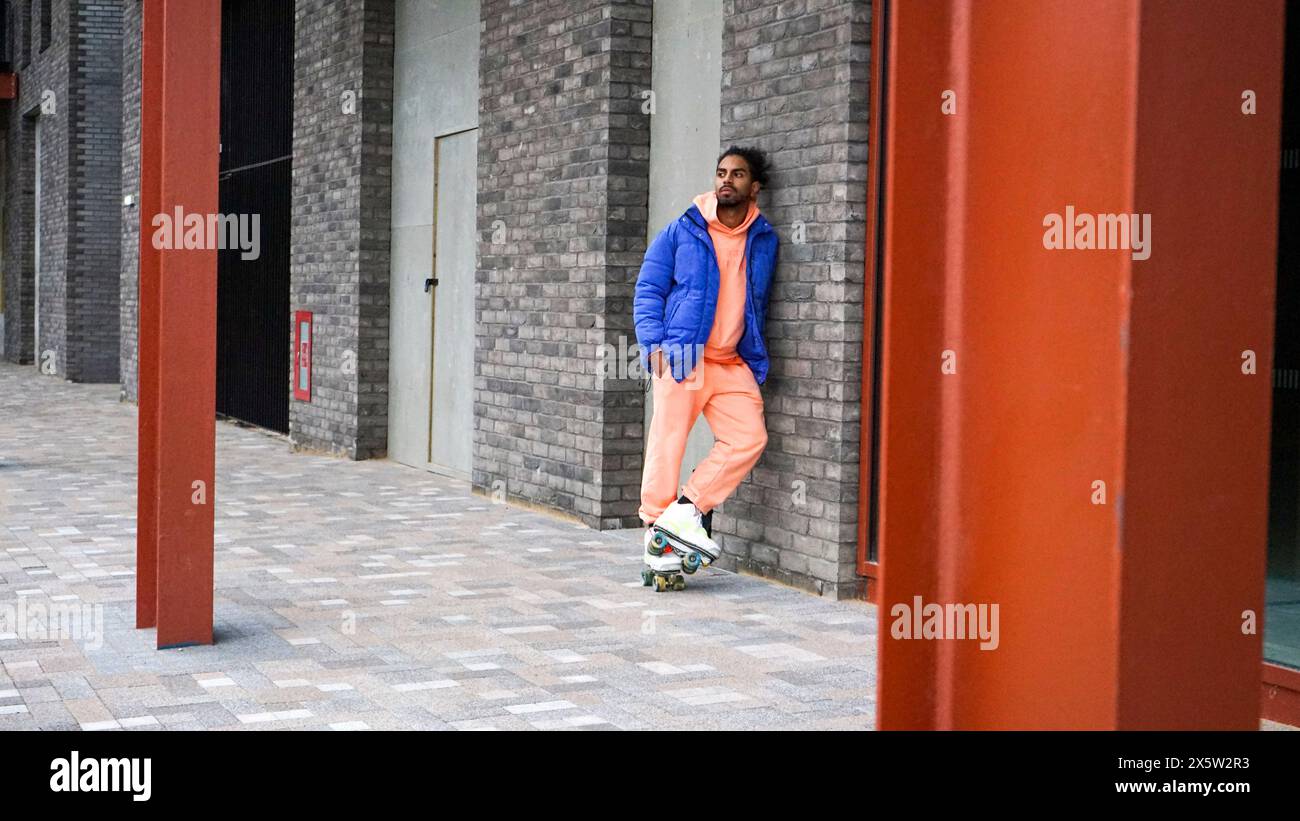 Jeune homme portant une veste bleue et des patins à roulettes Banque D'Images