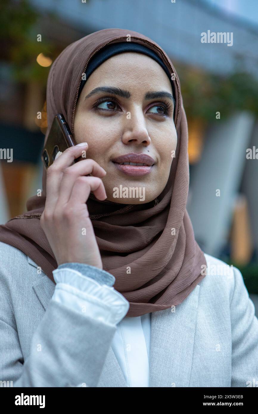Royaume-Uni, Londres, Portrait de femme d'affaires en hijab parlant sur téléphone intelligent Banque D'Images