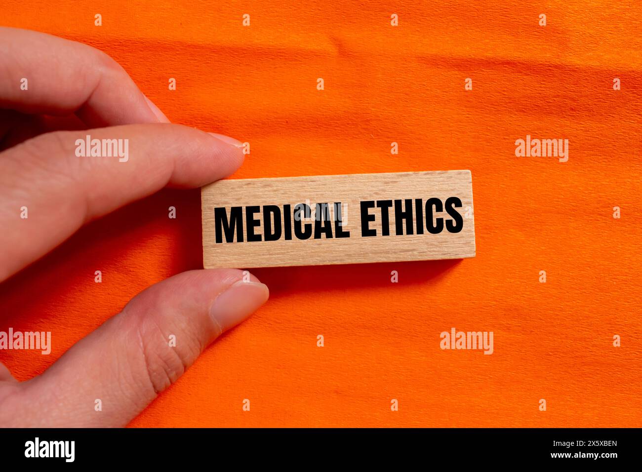Mots d'éthique médicale écrits sur bloc de bois avec fond orange. Symbole conceptuel de l'éthique médicale. Copier l'espace. Banque D'Images