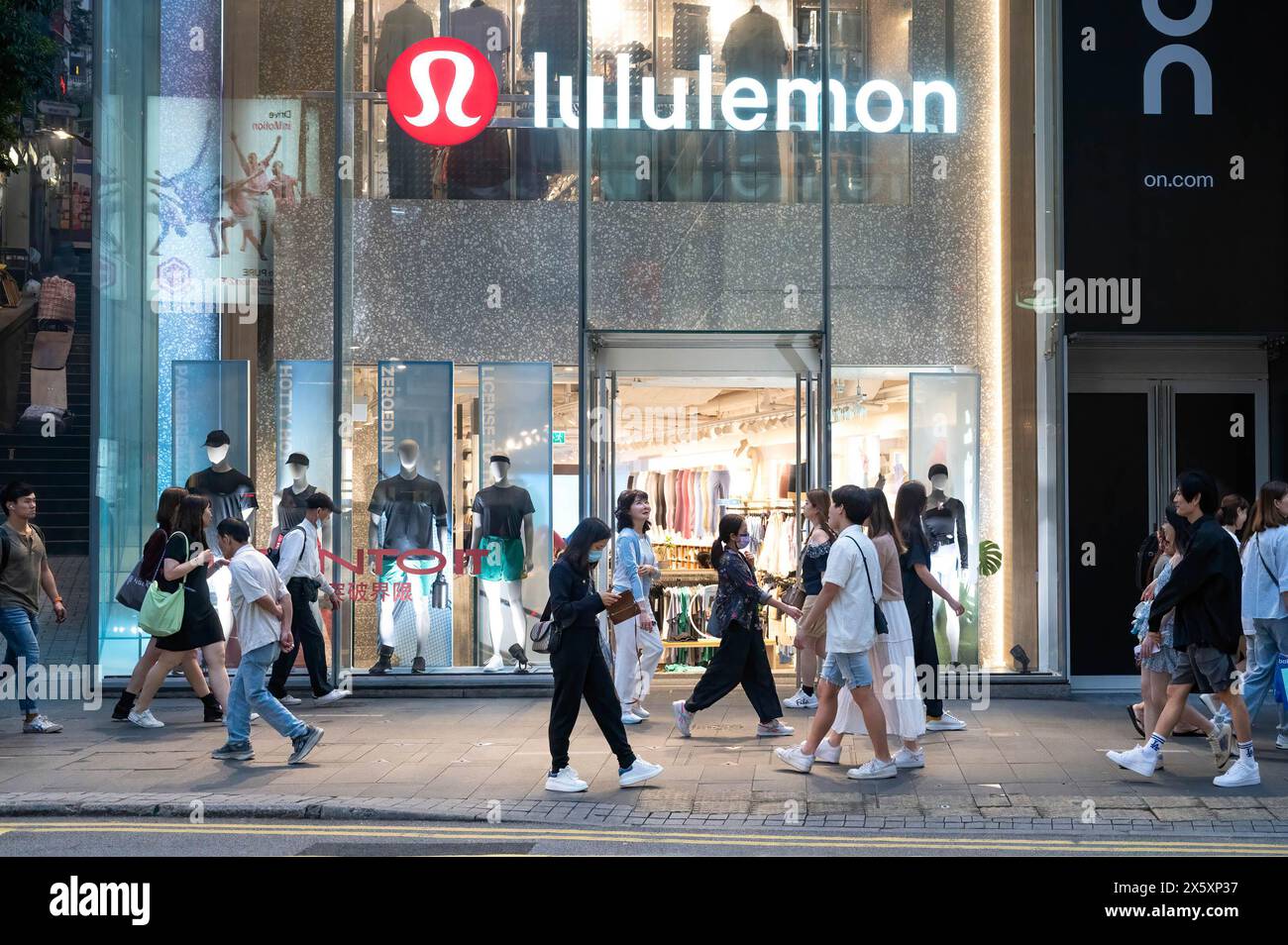 Les piétons passent devant le magasin de vêtements de sport canadien, Lululemon, à Hong Kong. Banque D'Images