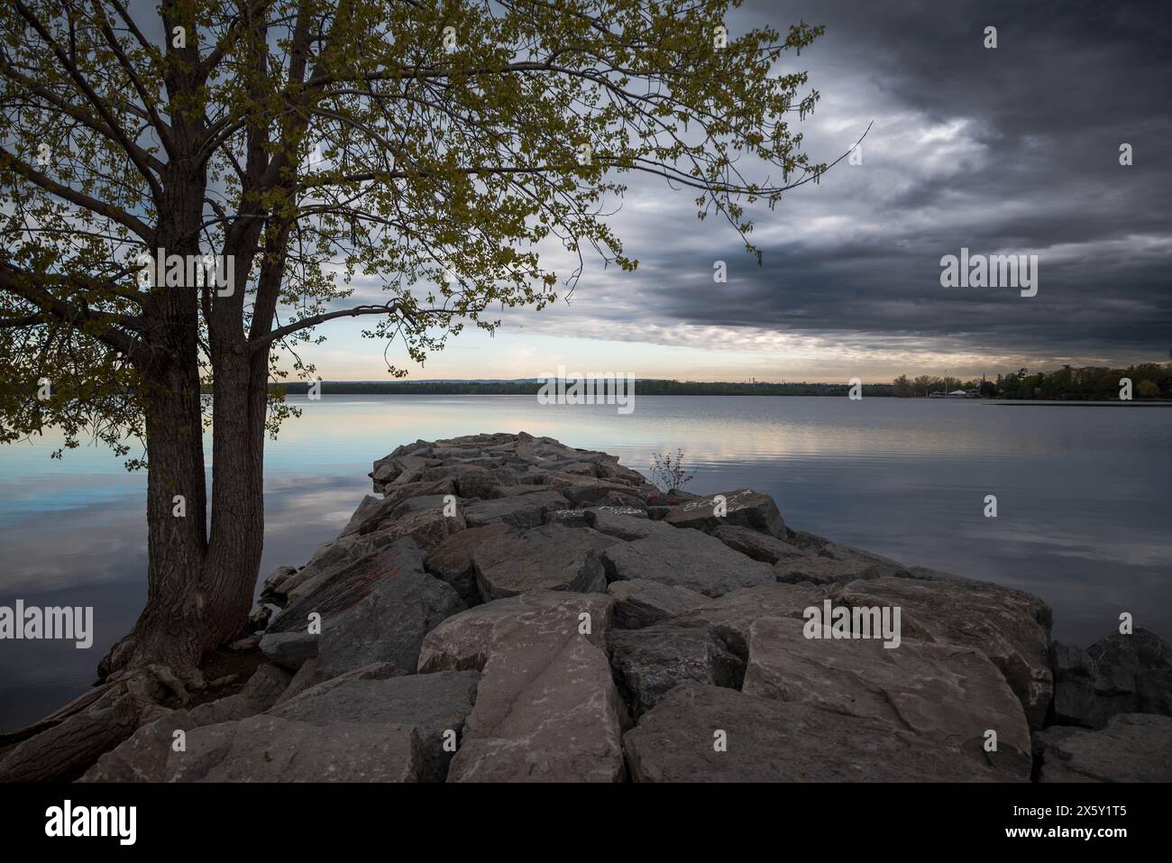 Serene Dusk at the Lakeside : une vue majestueuse sous un ciel orageux Banque D'Images