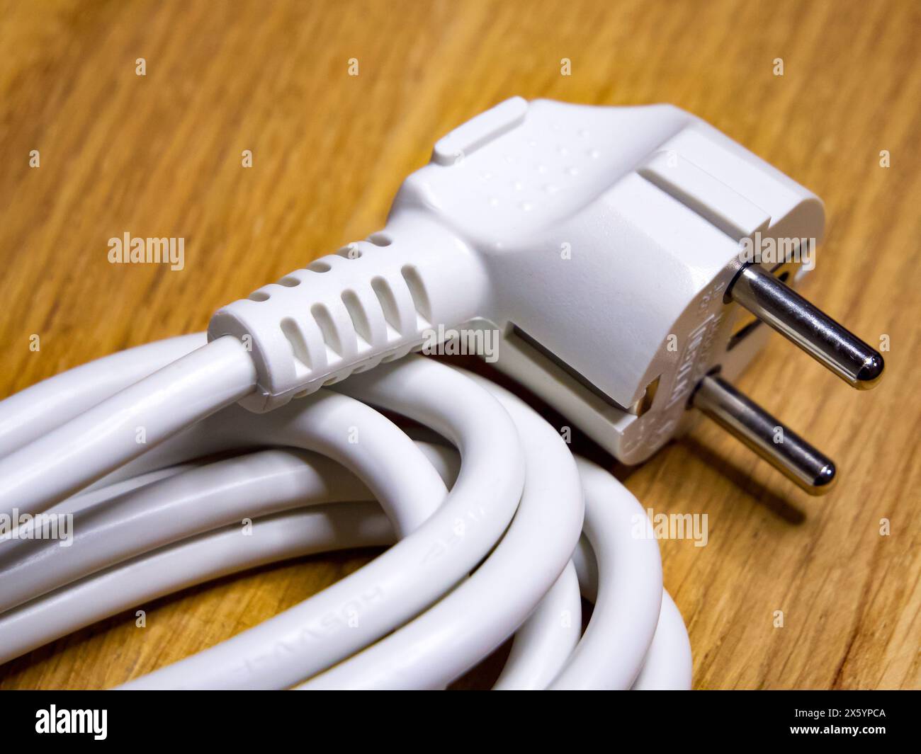 Nizhyn, Ukraine, 25 septembre 2021. Un cordon d'alimentation blanc avec une fiche à deux broches, enroulé sur une surface en bois, indiquant l'utilisation pour les appareils électroniques. Il Banque D'Images