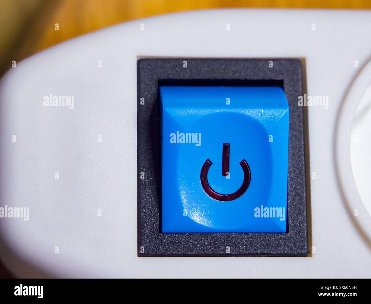 Un bouton d'alimentation bleu avec une icône d'alimentation, défini sur un appareil blanc, suggérant une fonctionnalité. Banque D'Images