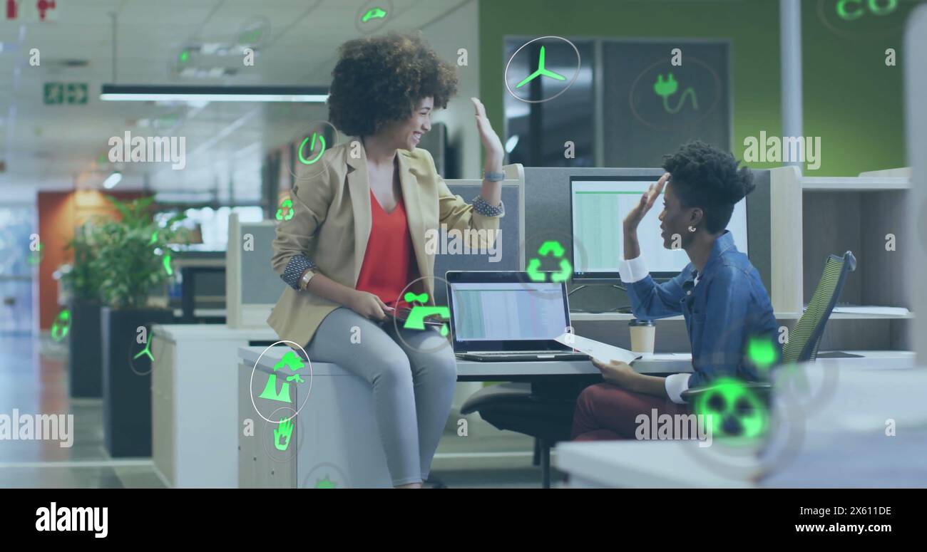 Image d'une icône dans des cercles au-dessus de diverses collègues féminines discutant et donnant haut cinq sur le bureau Banque D'Images
