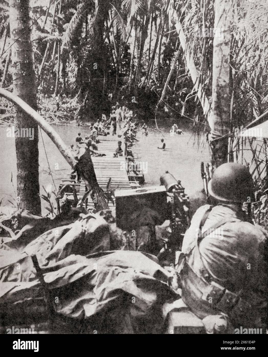 Les soldats alliés construisent un pont dans le Pacifique Sud lors de la retraite japonaise en Nouvelle-Guinée. Un mitrailleur surveille les patrouilles et les tireurs d'élite japonais, octobre 1943. De la Guerre en images, cinquième année. Banque D'Images