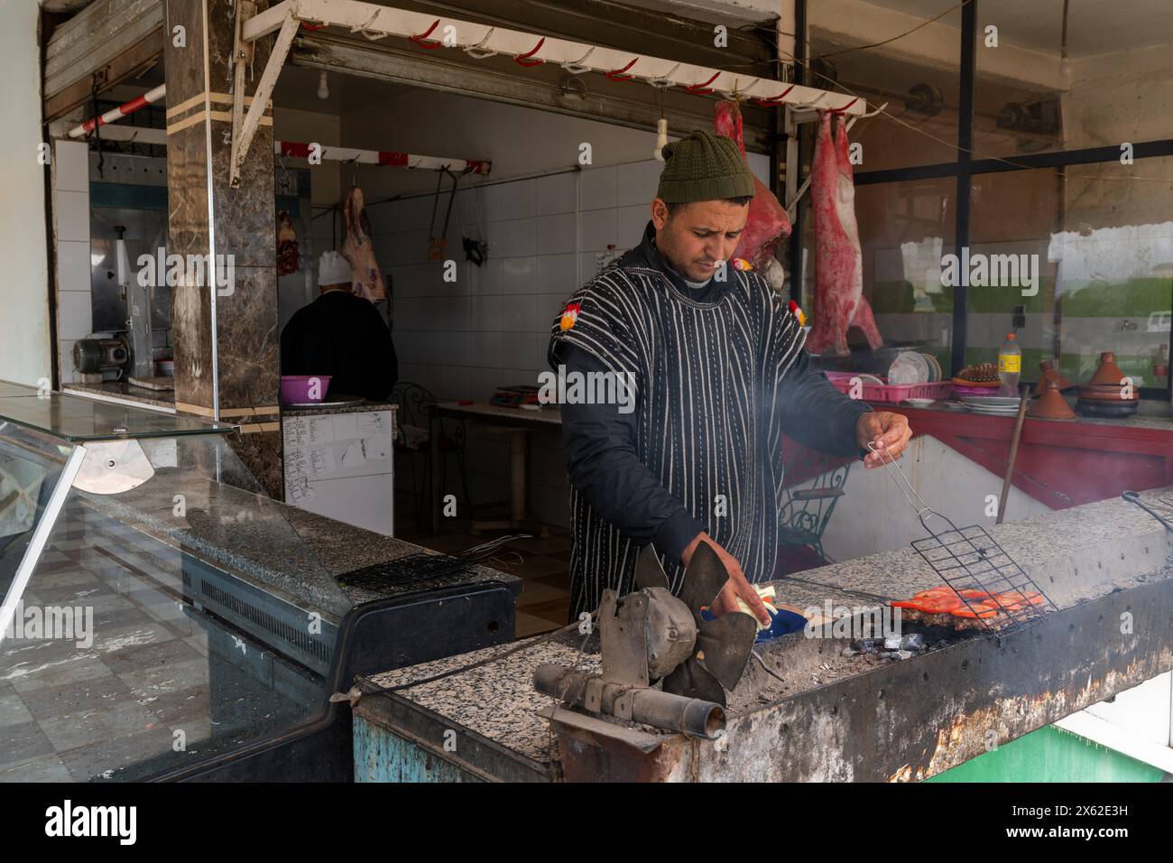 Moulay Yacoub, Maroc - 3 mars 2024 : un homme berbère grillant des boulettes de viande marocaines ou du Kefta Mkaoura dans sa cuisine près de Moulay Yacoub Banque D'Images