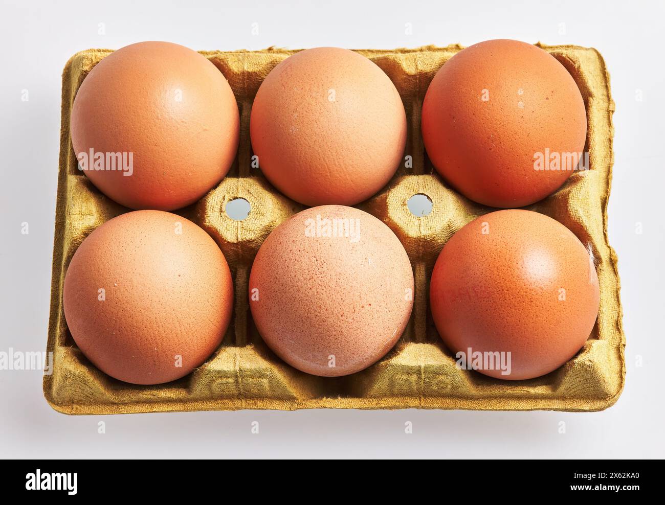Gros plan d'œufs bruns frais dans un plateau en carton doré sur fond blanc, indiquant bio, épicerie, petit déjeuner et nutrition. Banque D'Images