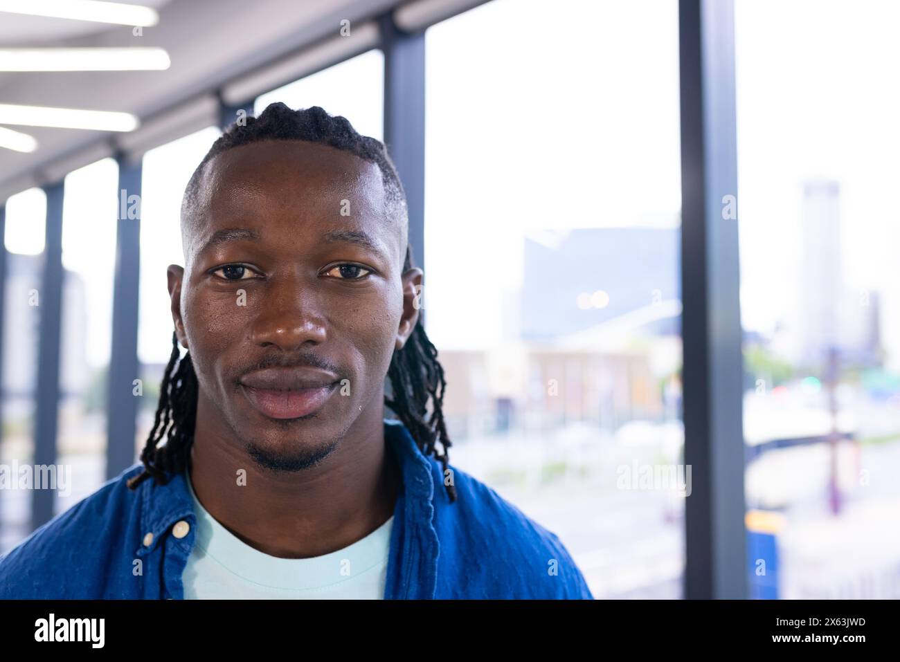 Dans le bureau moderne, jeune homme afro-américain avec les cheveux tressés debout, espace de copie Banque D'Images