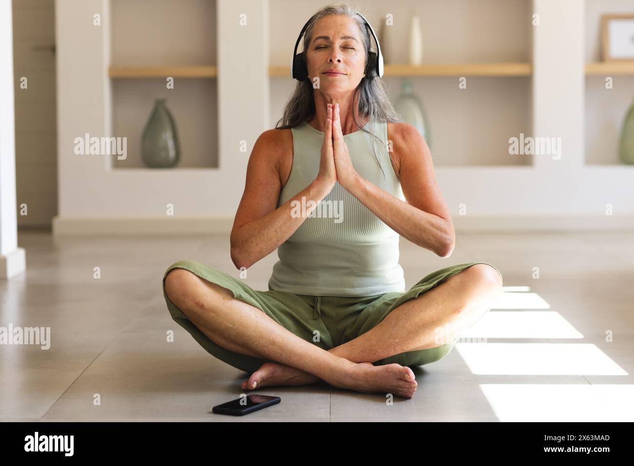 À la maison, femme caucasienne mature aux cheveux gris pratiquant le yoga Banque D'Images