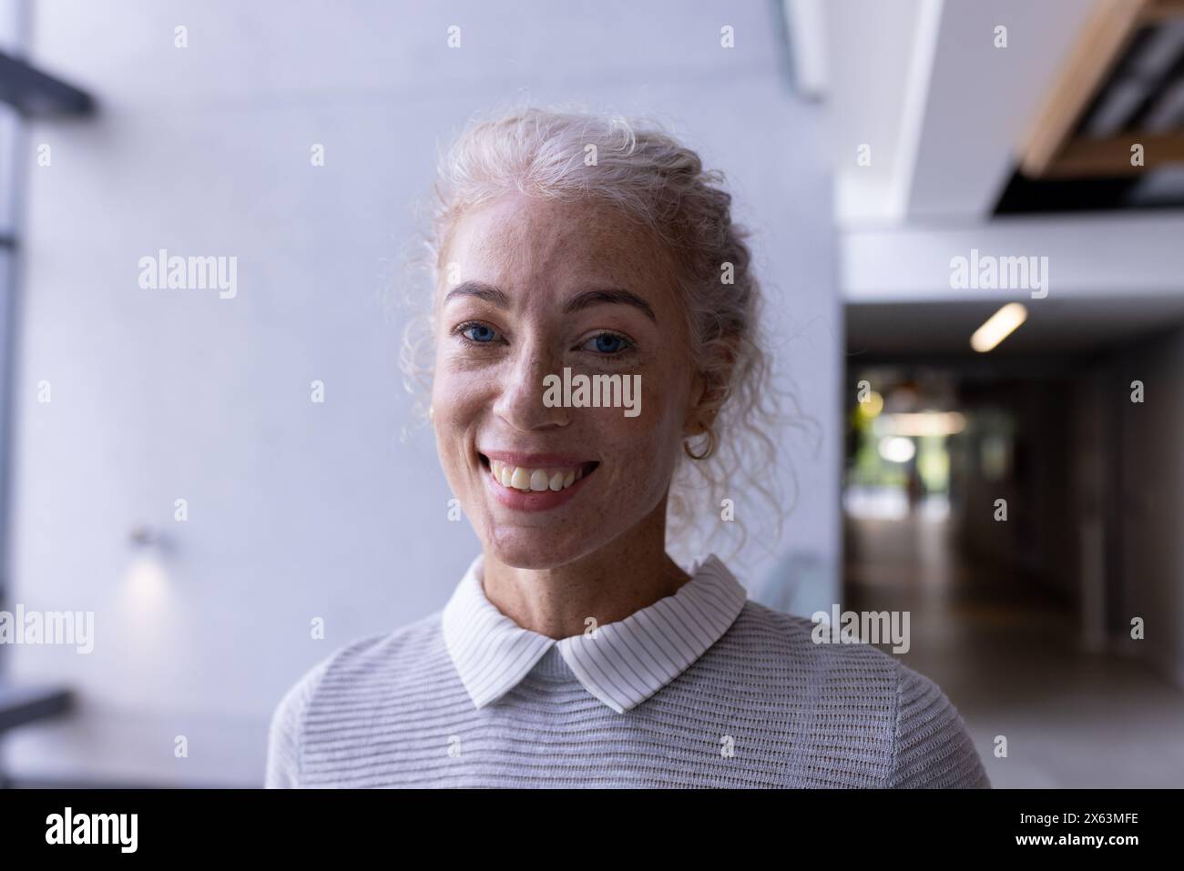 Une professionnelle caucasienne d'âge moyen souriant dans le couloir au bureau Banque D'Images