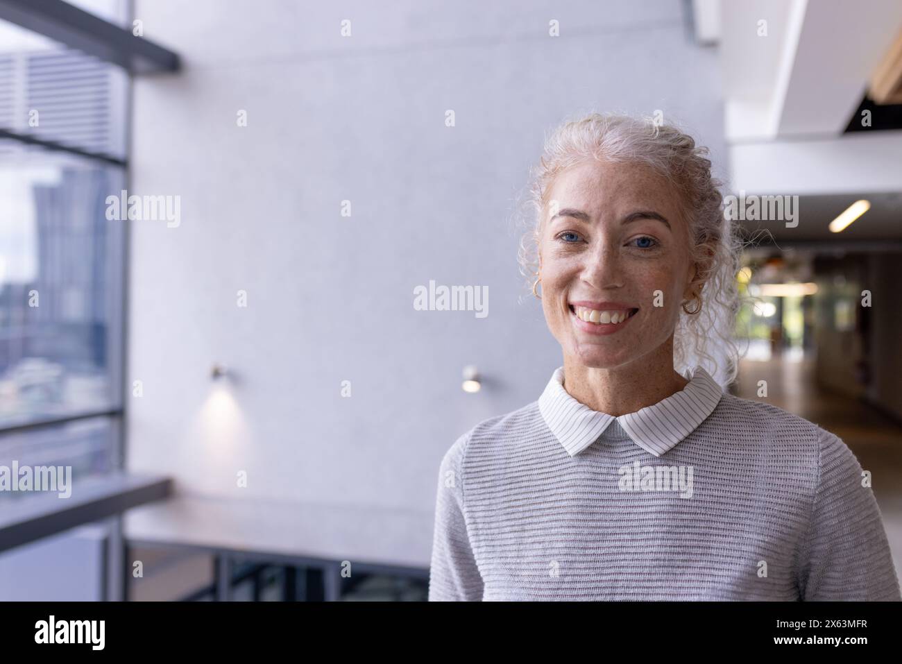 Une femme caucasienne d'âge moyen souriant au bureau, debout à l'intérieur, copiez l'espace Banque D'Images