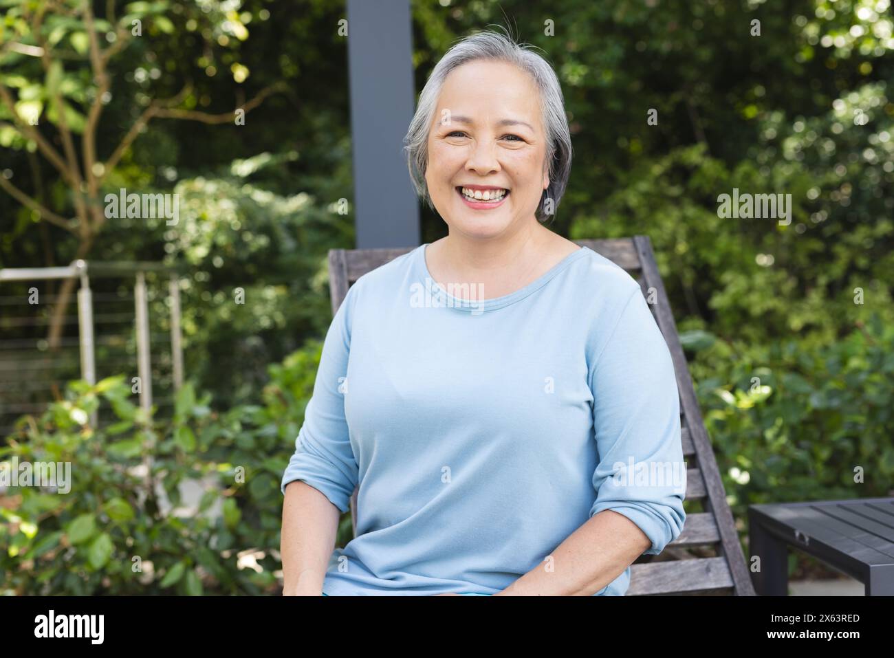 Femme senior asiatique assise à l'extérieur, souriant à la caméra Banque D'Images