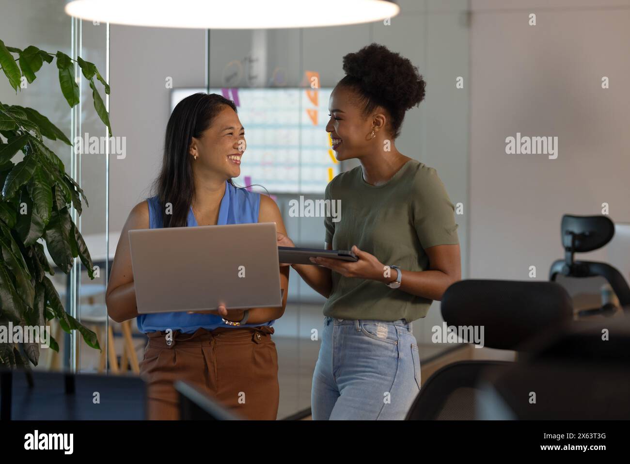 Au bureau, diverses collègues féminines discutent du travail, partagent un moment de lumière Banque D'Images