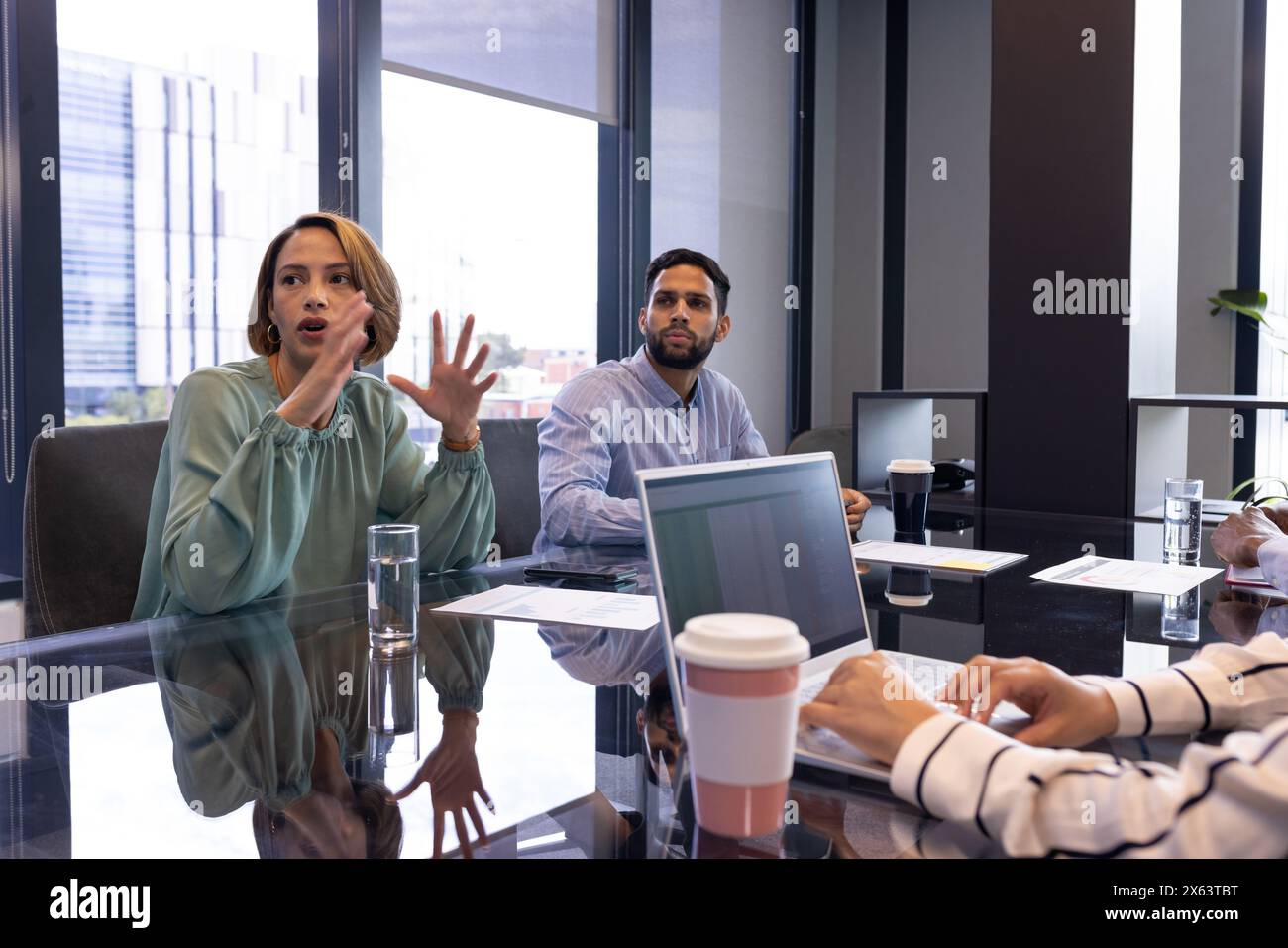 Équipe diversifiée s'engageant dans la réunion au bureau, femme portant un chemisier vert Banque D'Images
