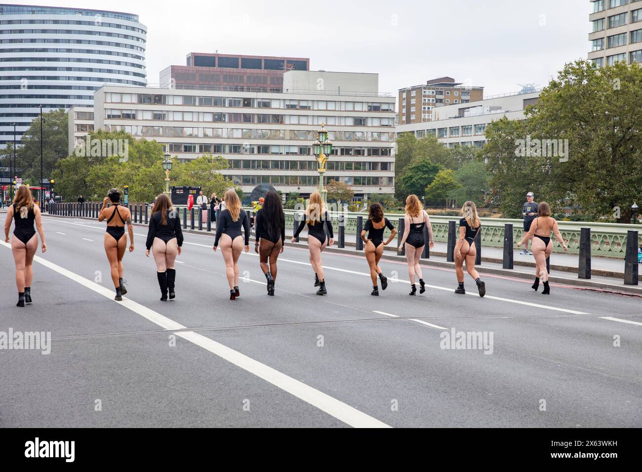 Vue arrière des filles en léotards noirs marchent le long du pont Westminster Londres vers l'hôpital universitaire St Thomas's NHS, les femmes protestent / pouvoir, Londres Banque D'Images