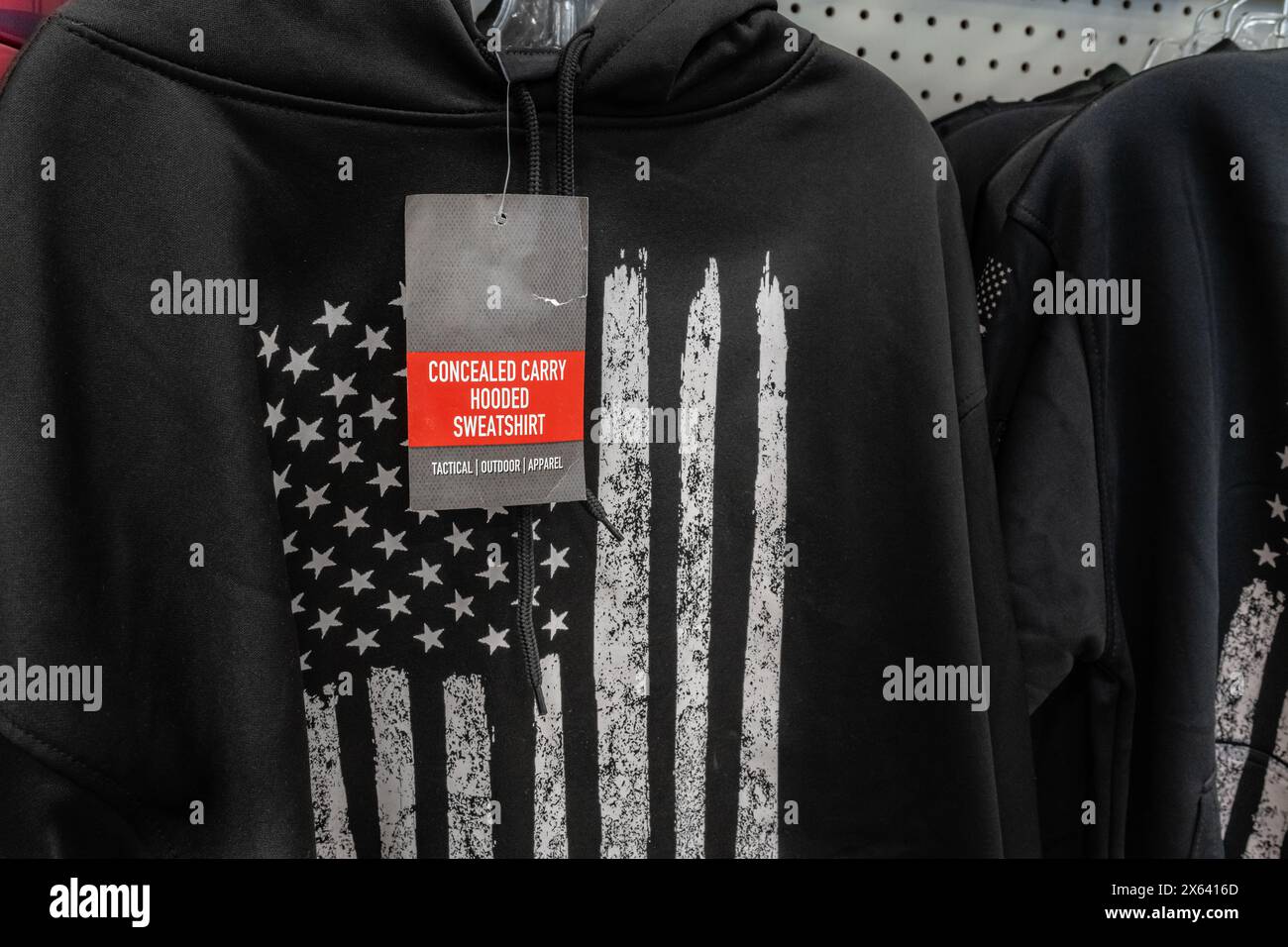 Gros plan du sweat-shirt noir caché à vendre dans un magasin de détail avec drapeau américain stylisé noir et blanc sur le devant du sweat-shirt. Banque D'Images