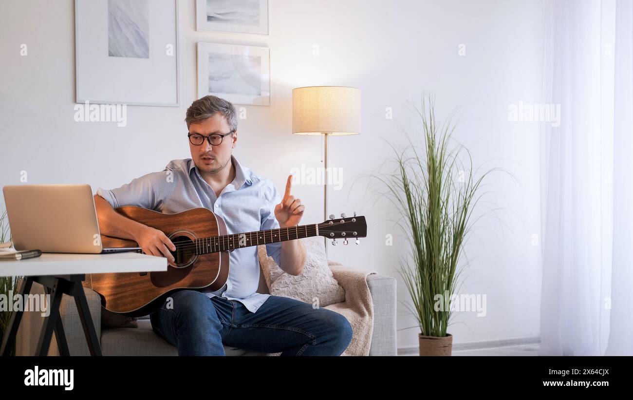 Cours de guitare. Éducation sur Internet. Entraîneur de musique spécialiste homme expliquant les accords jouant des règles à la distance vidéo portable webinaire appel à la maison espace de copie. Banque D'Images