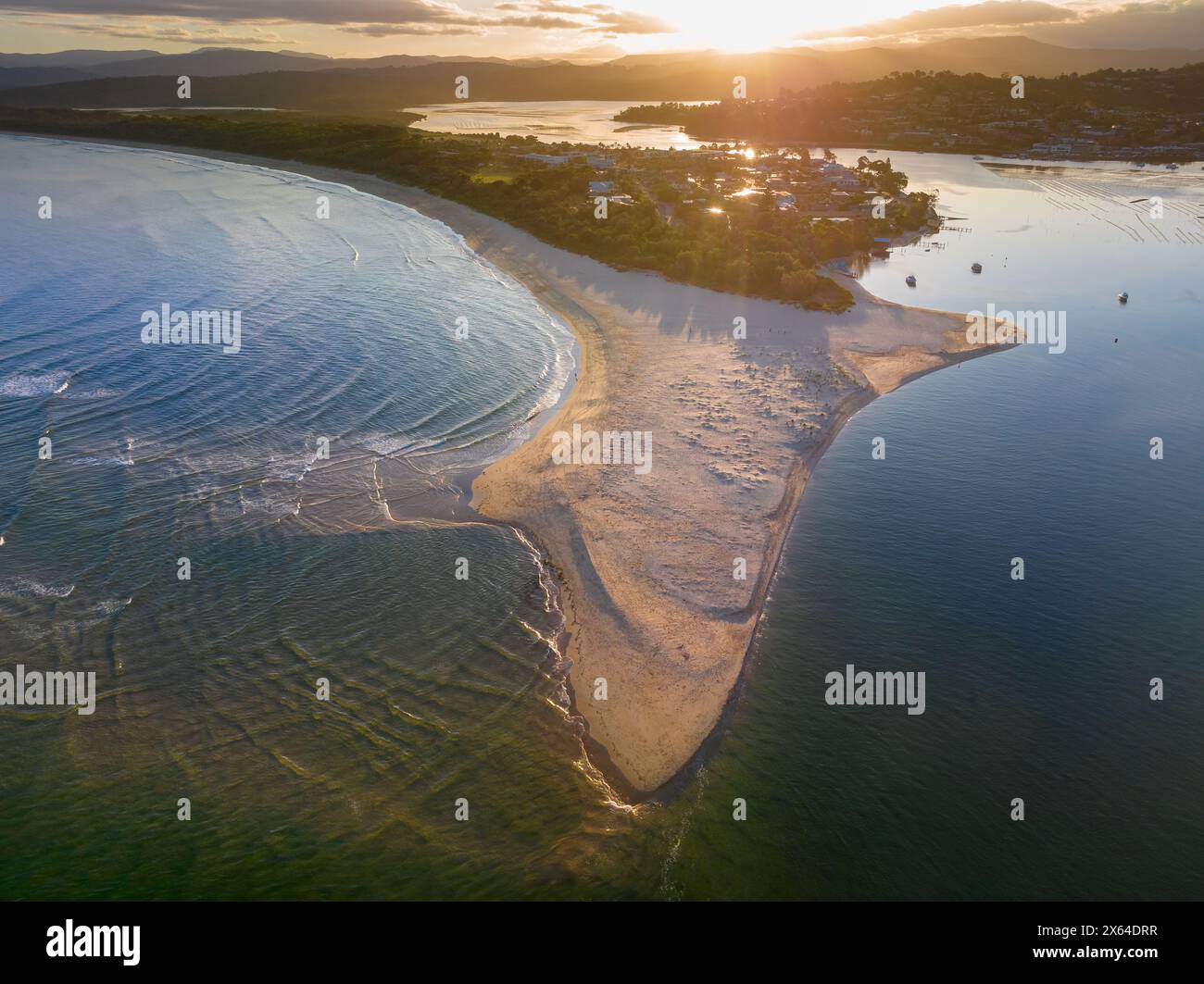 Vue aérienne du coucher de soleil sur une côte avec une longue barre de sable saillante à Merimbula en Nouvelle-Galles du Sud, Australie Banque D'Images