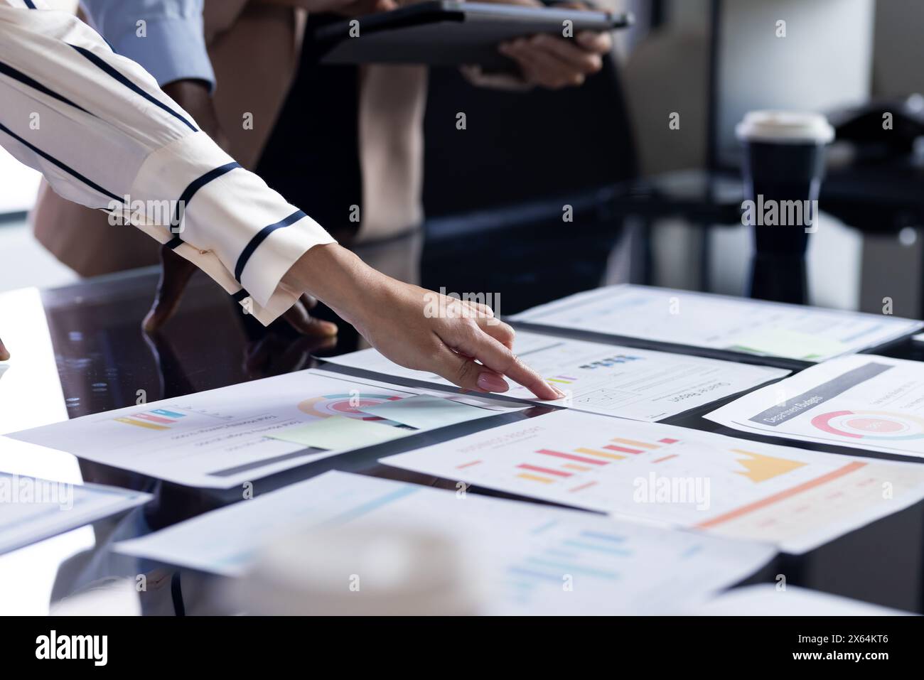 Une équipe diversifiée au bureau, y compris une femme caucasienne d'âge moyen, examinant des articles Banque D'Images