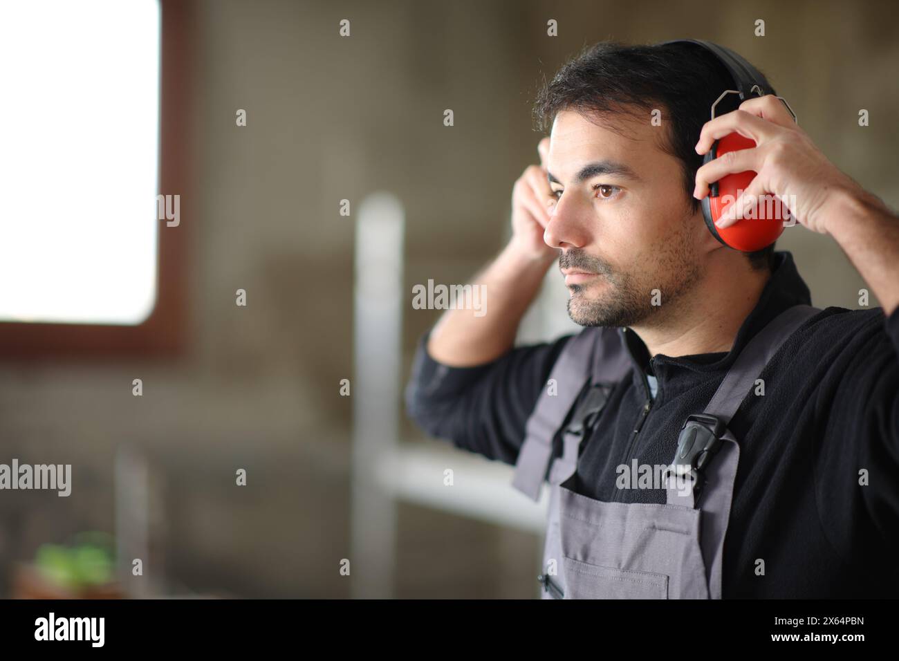 Travailleur de la Consruction mettant un casque antibruit dans une maison en rénovation Banque D'Images