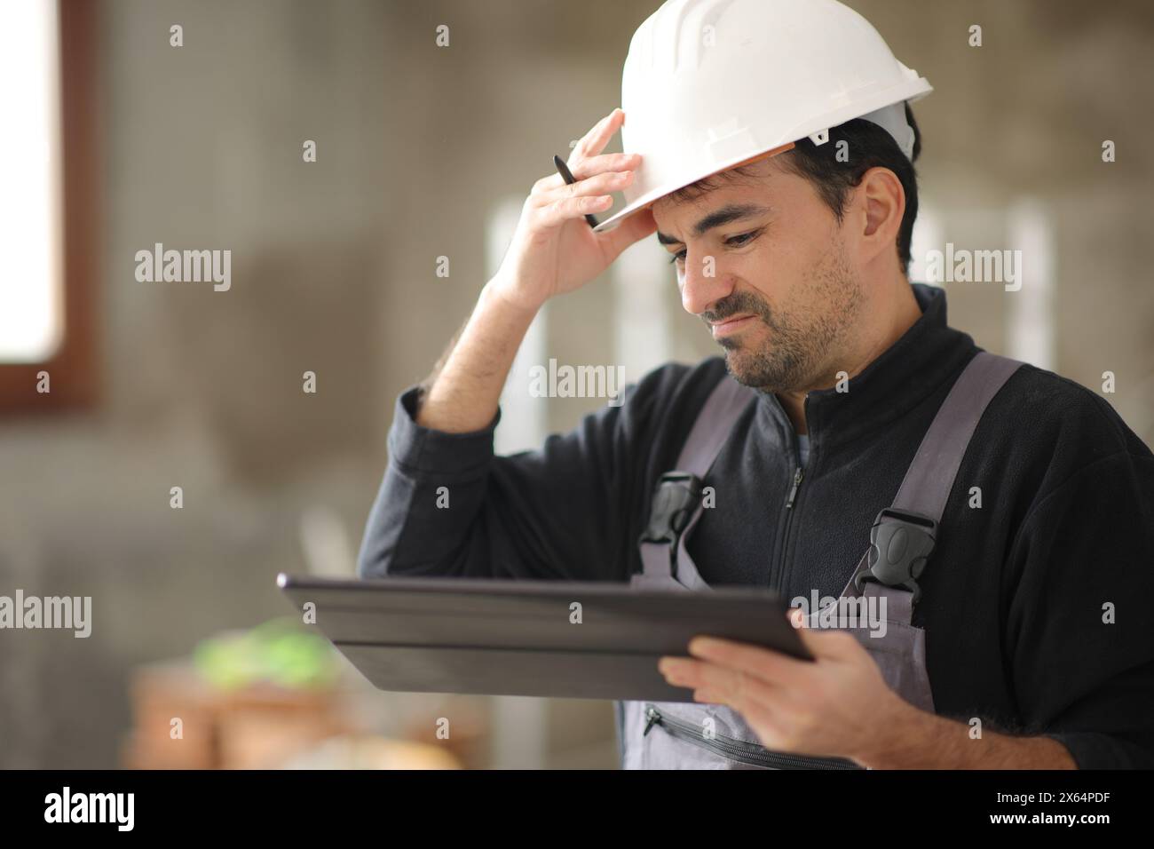 Travailleur de la construction déçu vérifiant la tablette dans une maison Banque D'Images