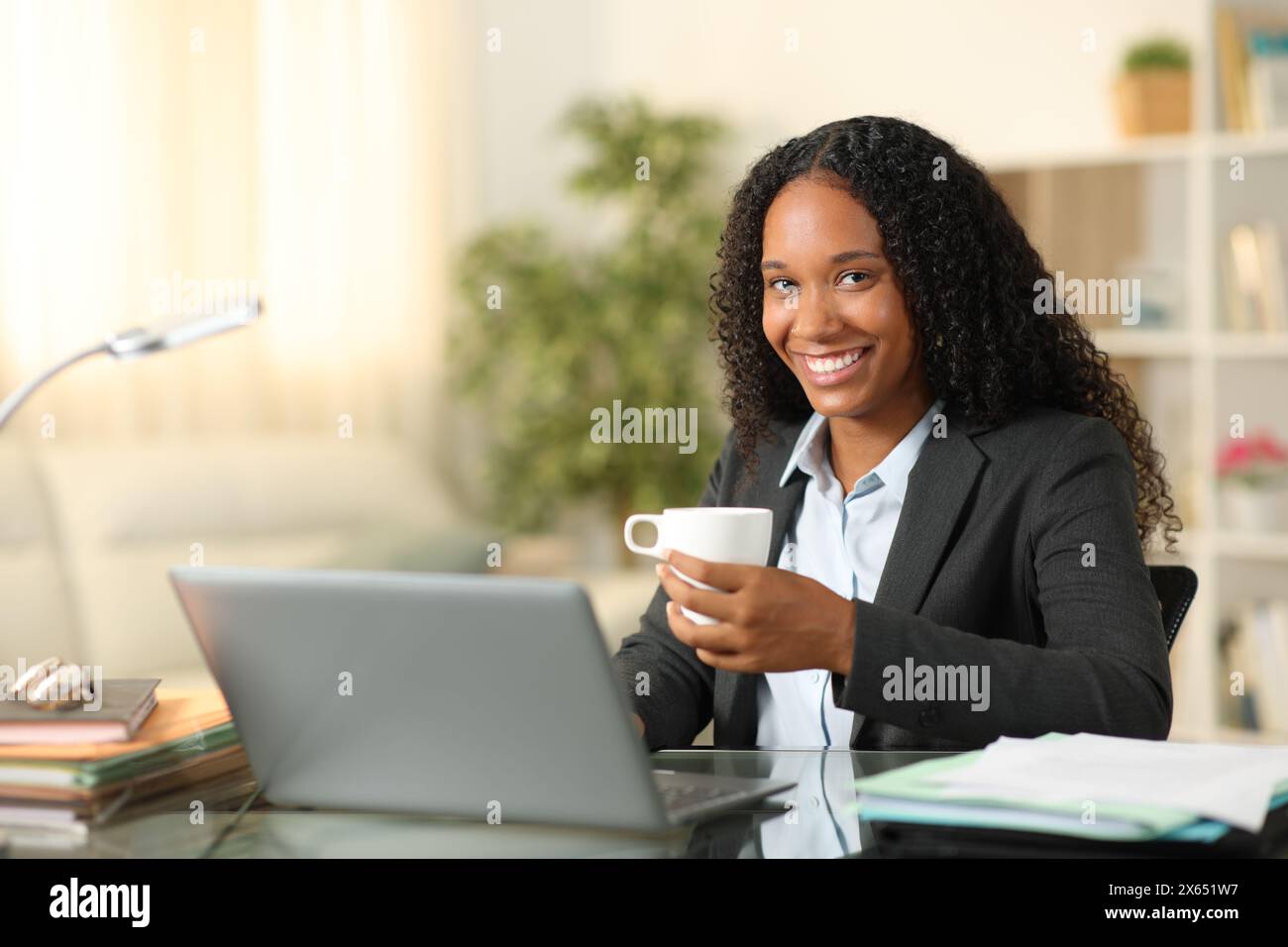 Heureux télétravailleur posant avec une tasse de café à la maison regardant la caméra Banque D'Images