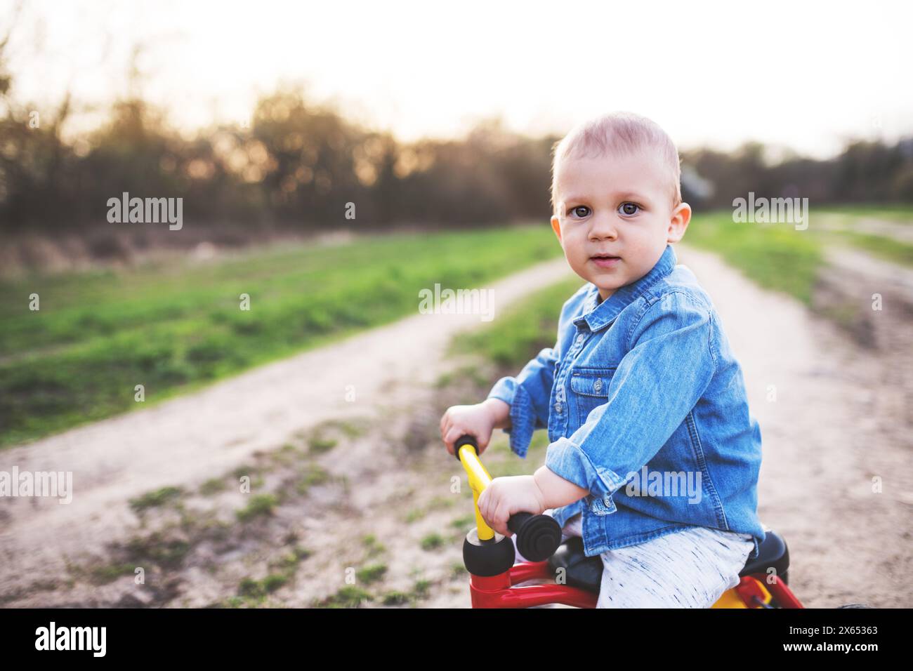 Portrait de tout-petit garçon apprenant tour bébé vélo. ou vélo d'équilibre. Banque D'Images