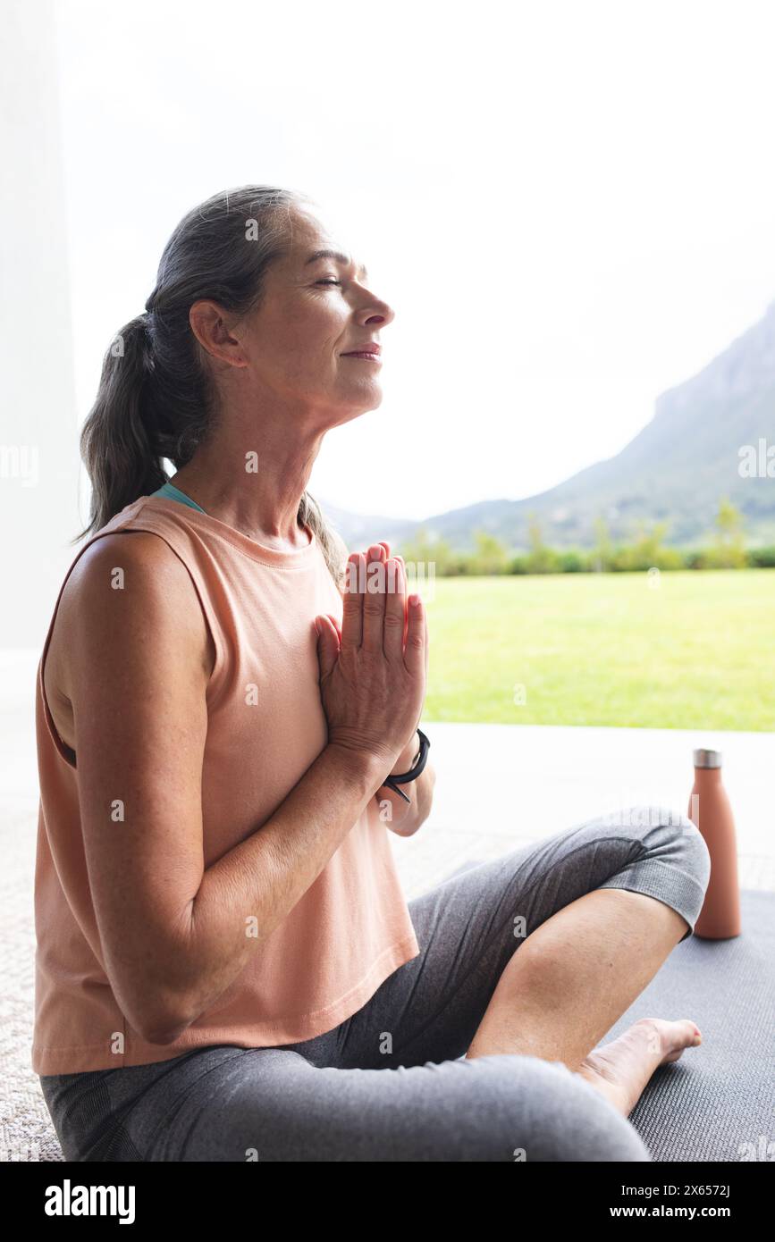 À la maison, femme caucasienne mature aux cheveux gris pratiquant le yoga Banque D'Images