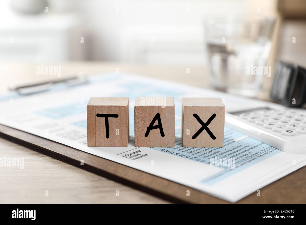 Cubes en bois avec le mot taxe et document sur la table, gros plan Banque D'Images