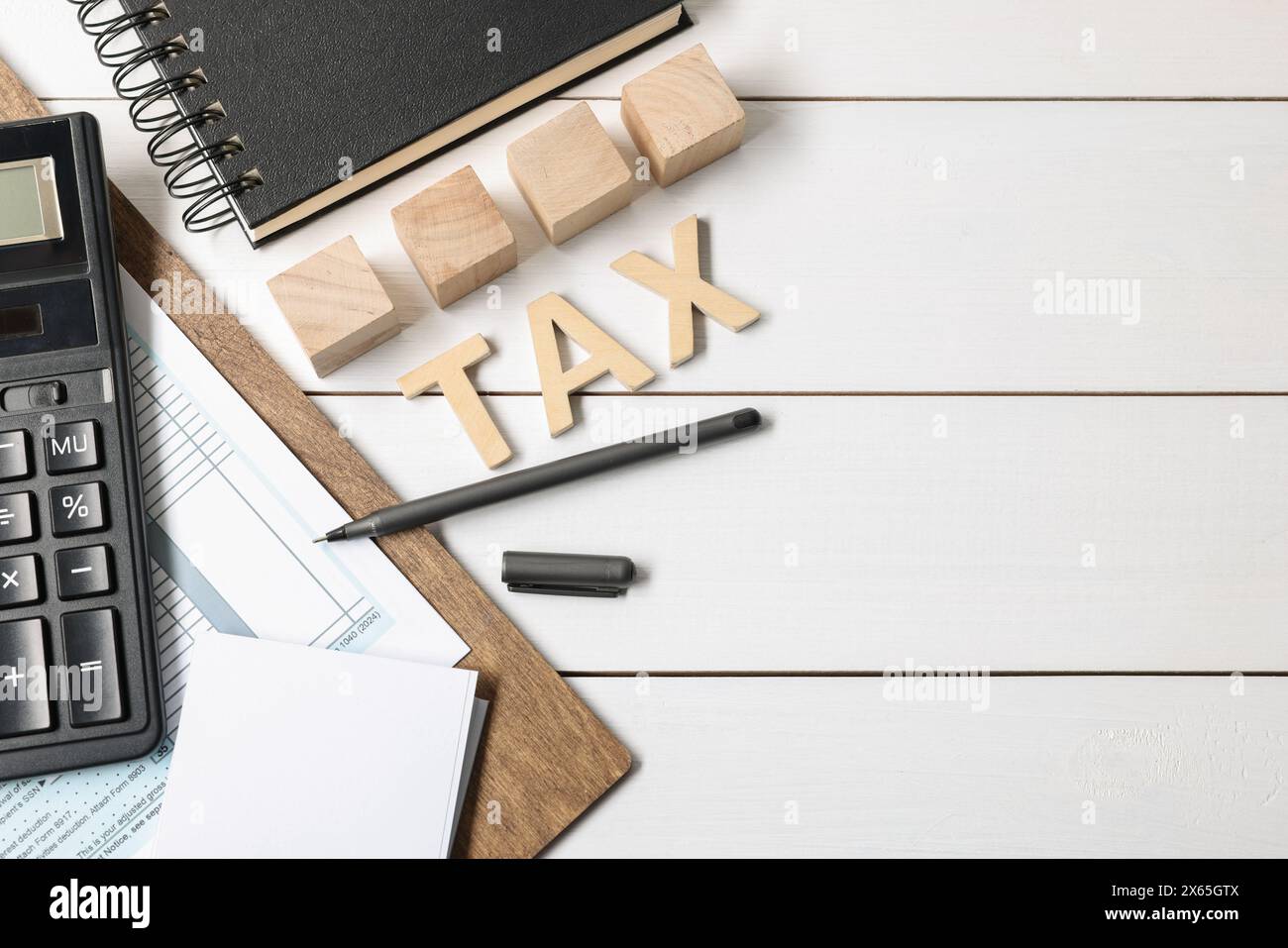 Word Tax fait de lettres, cubes, calculatrice, cahier et documents sur table en bois blanc, pose à plat. Espace pour le texte Banque D'Images