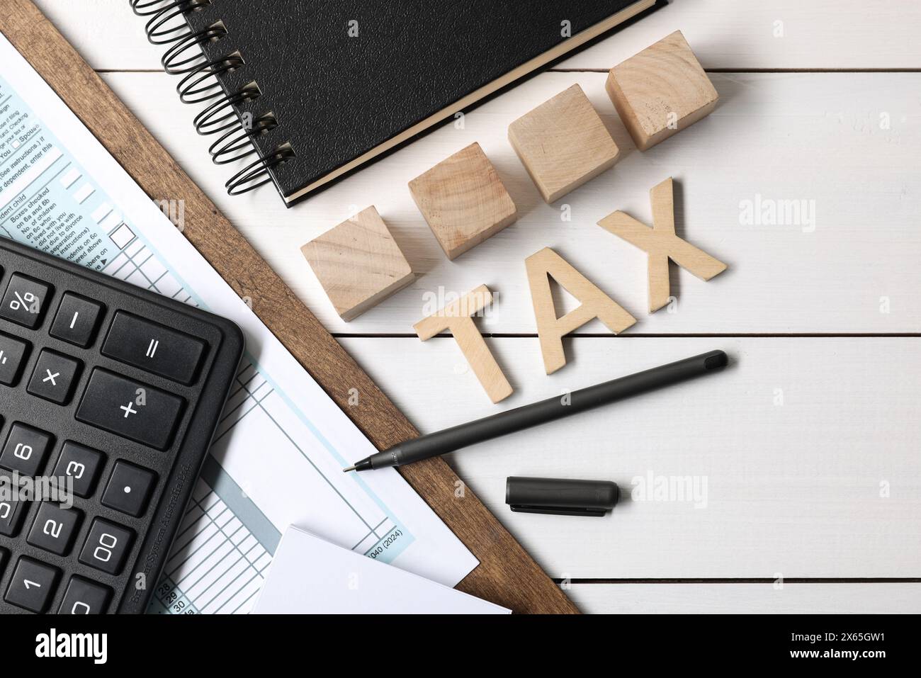 Word Tax fait de lettres, cubes, calculatrice, cahier et documents sur table en bois blanc, pose à plat Banque D'Images