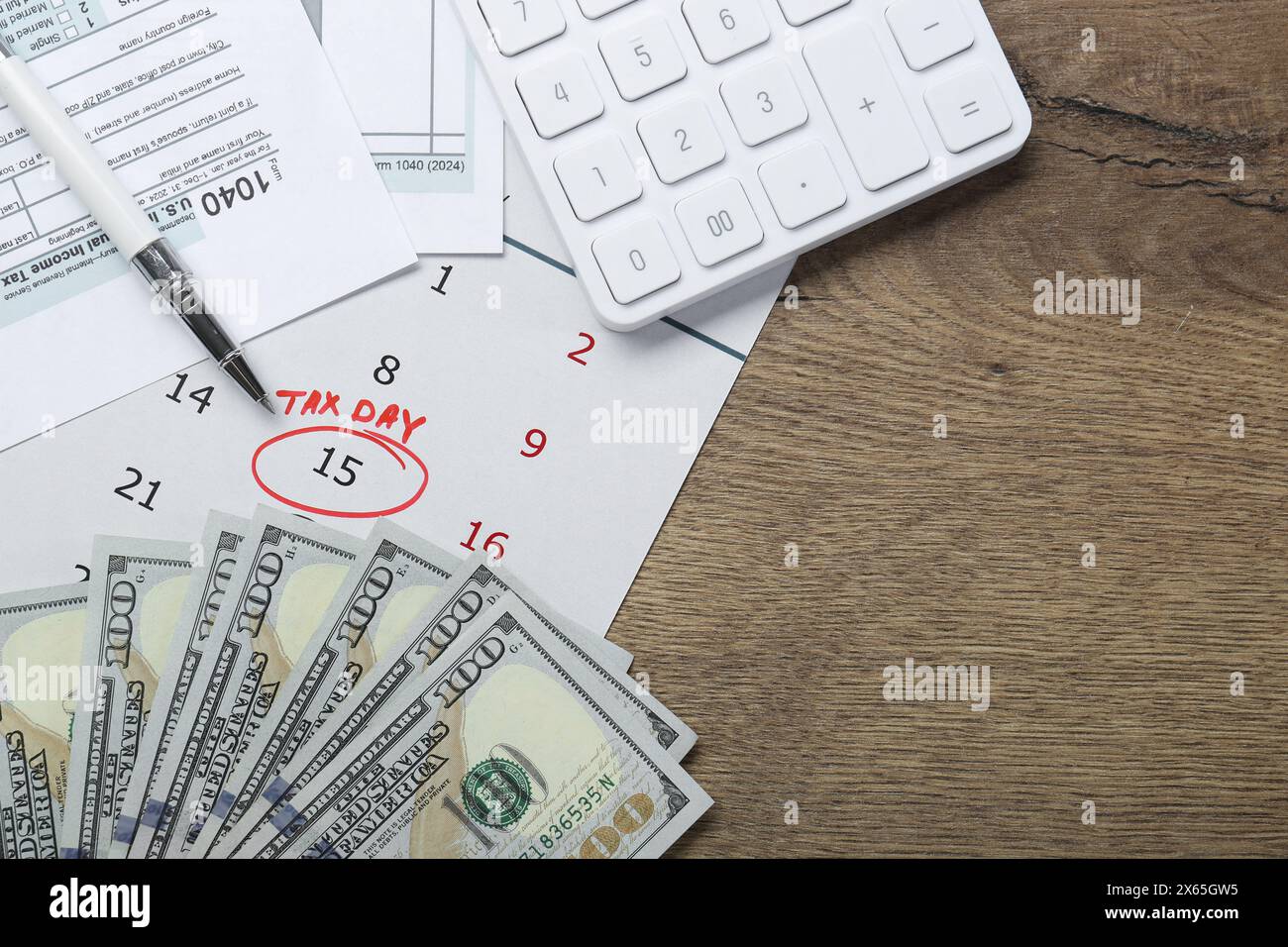 Calendrier avec rappel de date sur le jour d'imposition, documents, stylo, argent et calculatrice sur table en bois, pose à plat. Espace pour le texte Banque D'Images