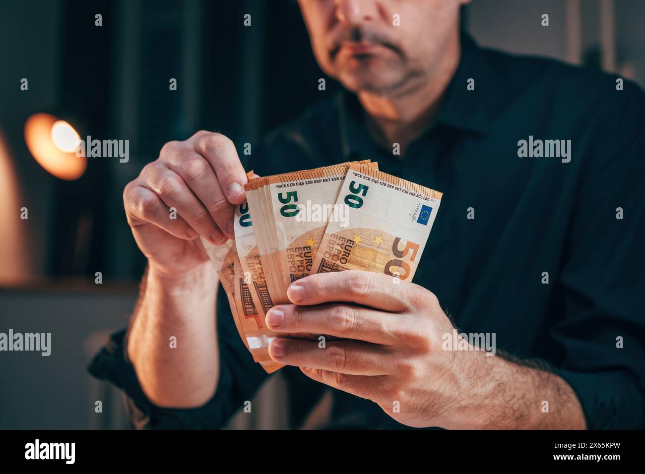 Homme d'affaires comptant cinquante billets en euros tard dans la nuit dans son bureau, focus sélectif Banque D'Images