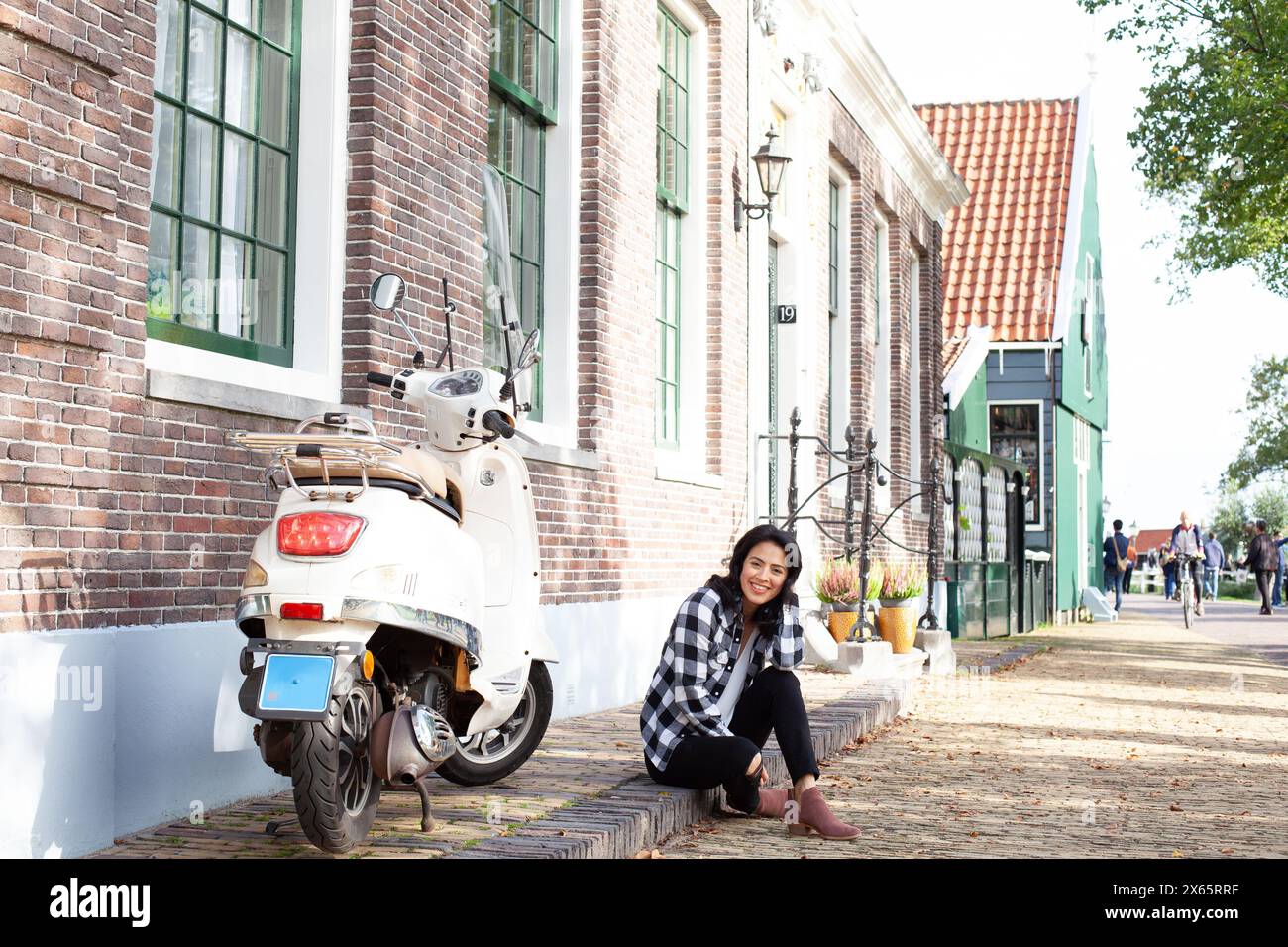 Femme assise sur le trottoir à côté d'un cyclomoteur à Amsterdam Banque D'Images