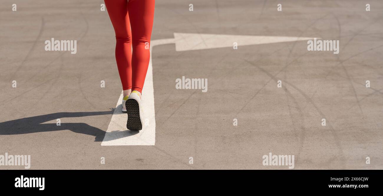 gros plan, vue arrière d'une femme coureuse avec une flèche peinte sur la route Banque D'Images
