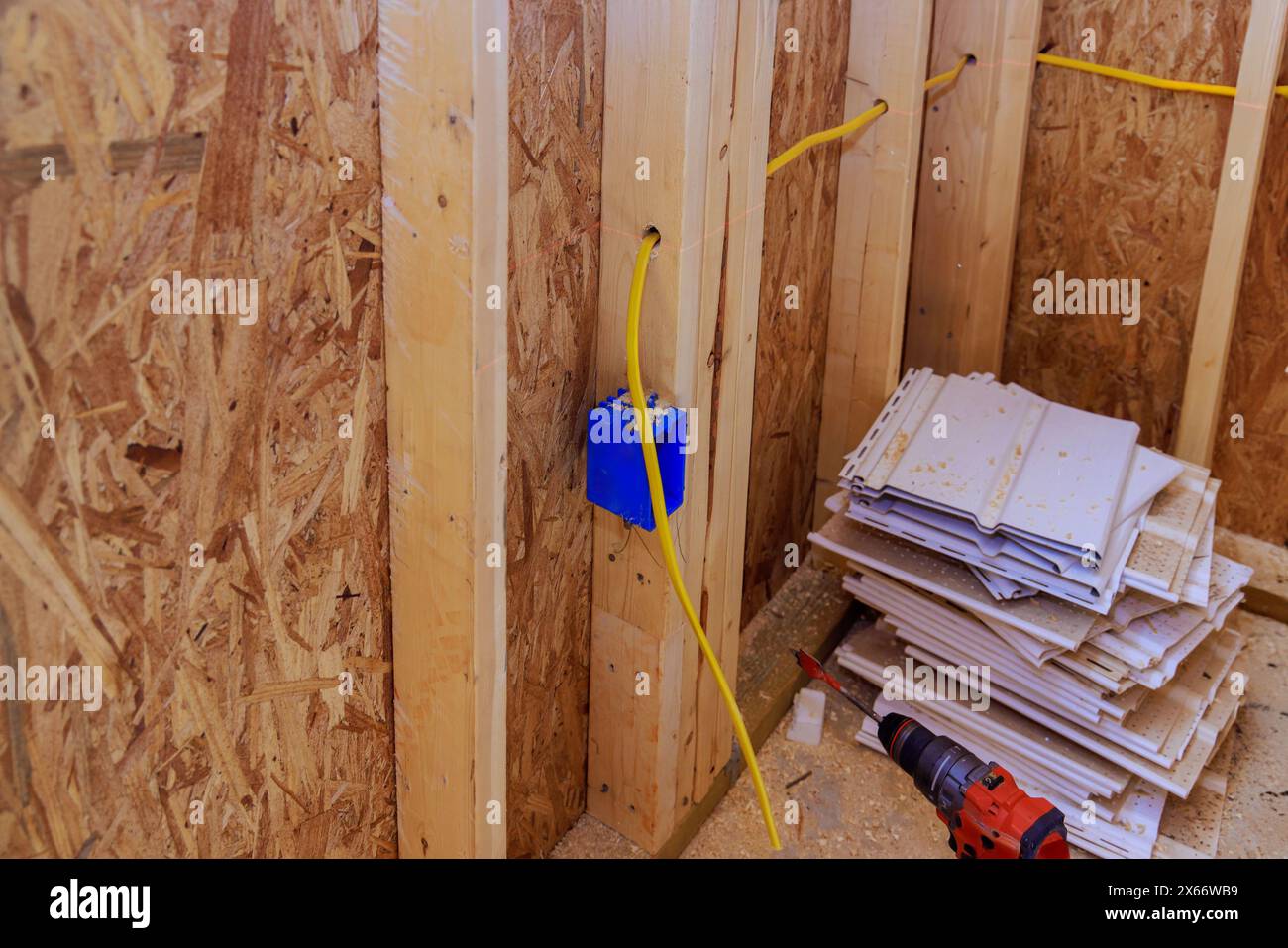 Un électricien installe des fils électriques assemblés à l'intérieur d'un chantier de construction Banque D'Images