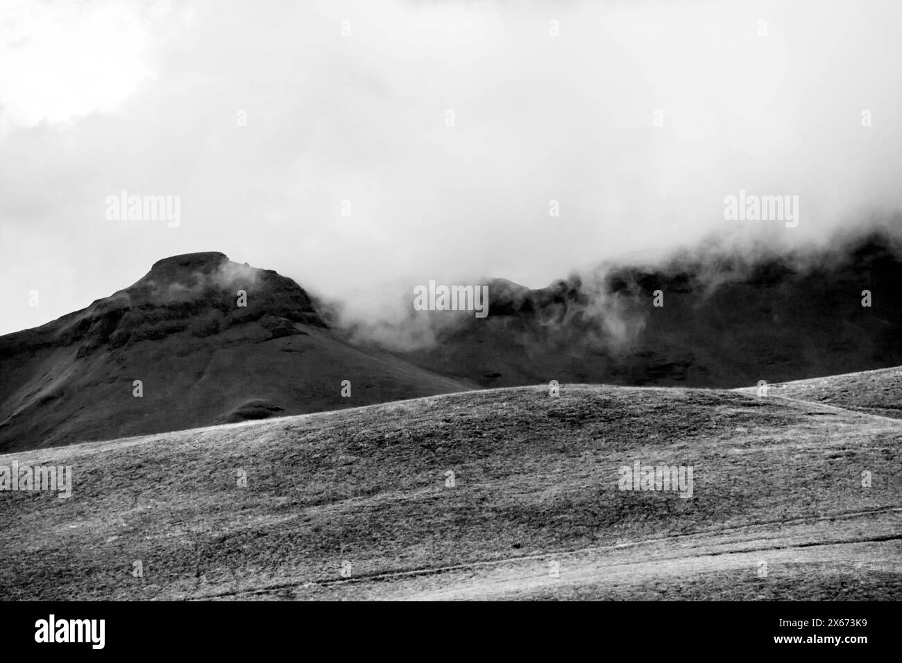 Les nuages commencent à couler sur les montagnes de la chaîne de montagnes du Drakensberg en Afrique du Sud, en noir et blanc Banque D'Images