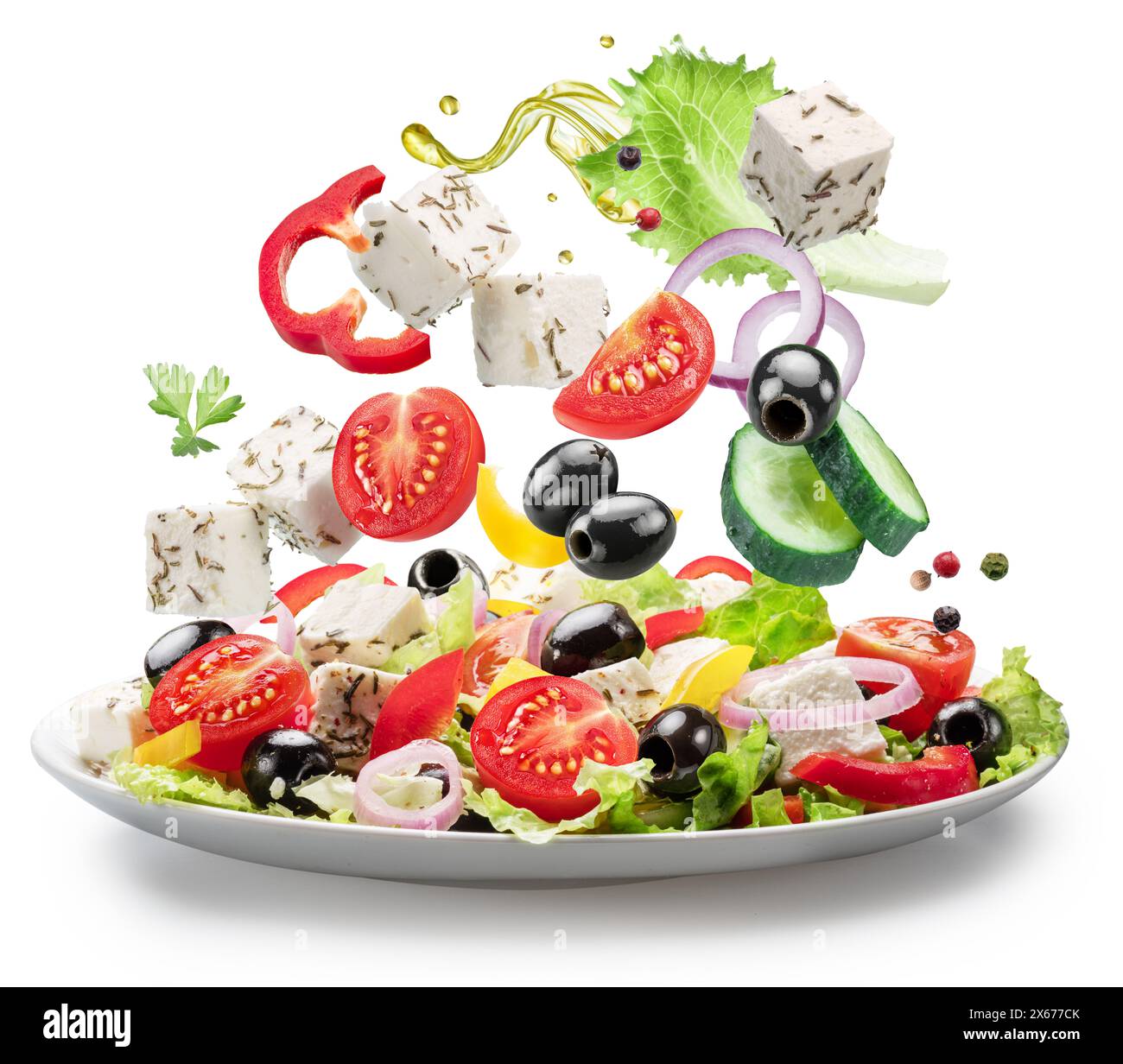 Légumes frais et fromage feta tombant dans la plaque blanche isolé. Le fichier contient des chemins de détourage. Banque D'Images